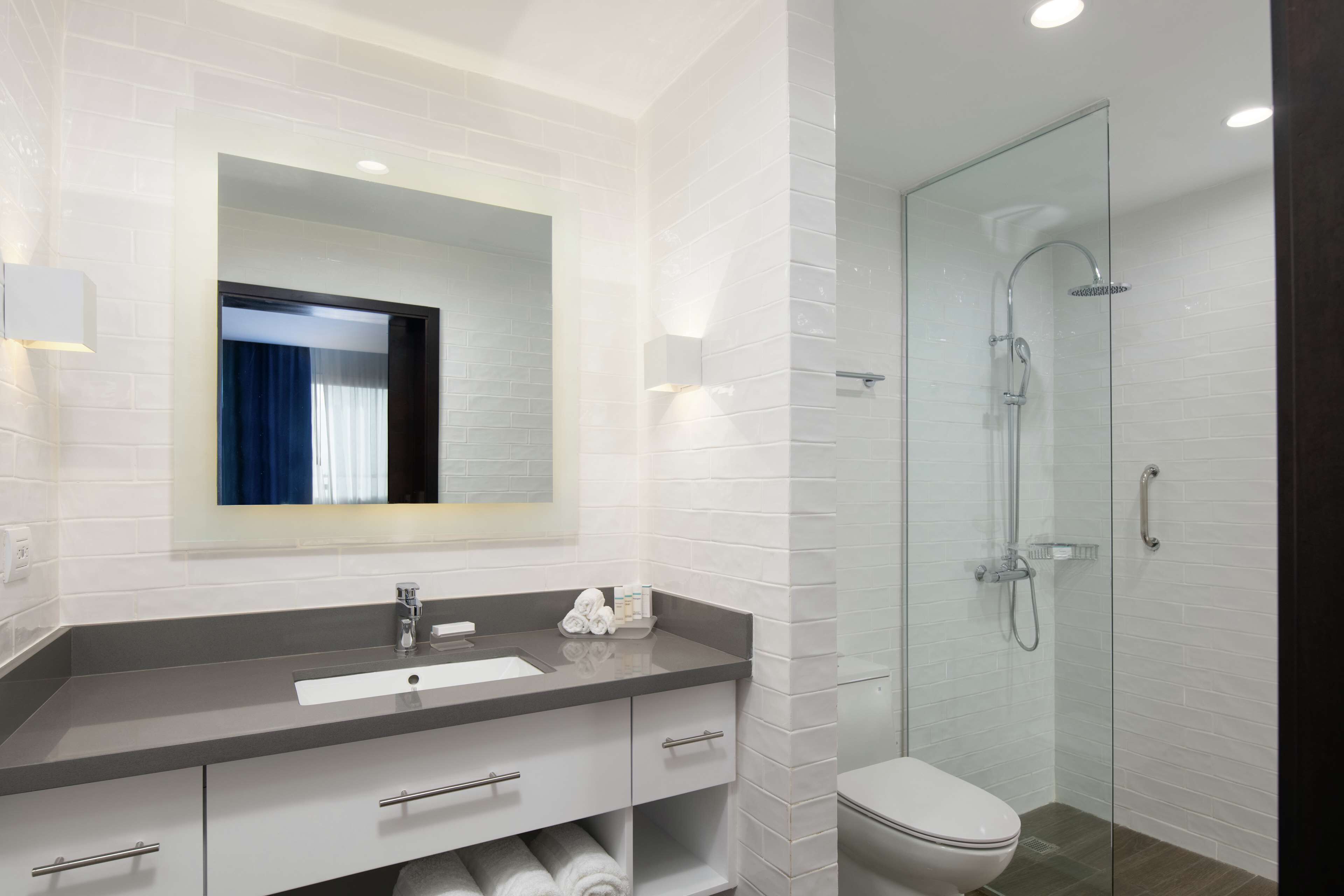 Une salle de bain moderne avec un lavabo gris, un meuble-lavabo blanc, une cabine de douche en verre et des toilettes blanches.