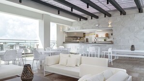 Un espacio moderno con sala, sillas de comedor y una cocina al fondo.