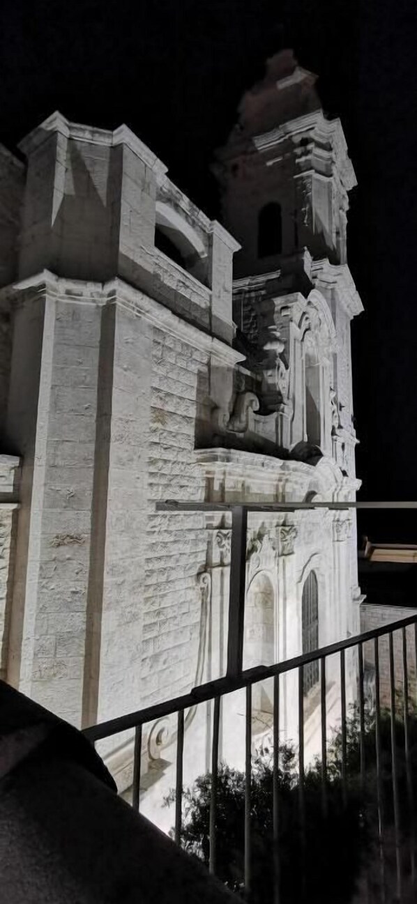 A historic building with a bell tower, possibly a church or cathedral, with a balcony and a fence in the foreground.