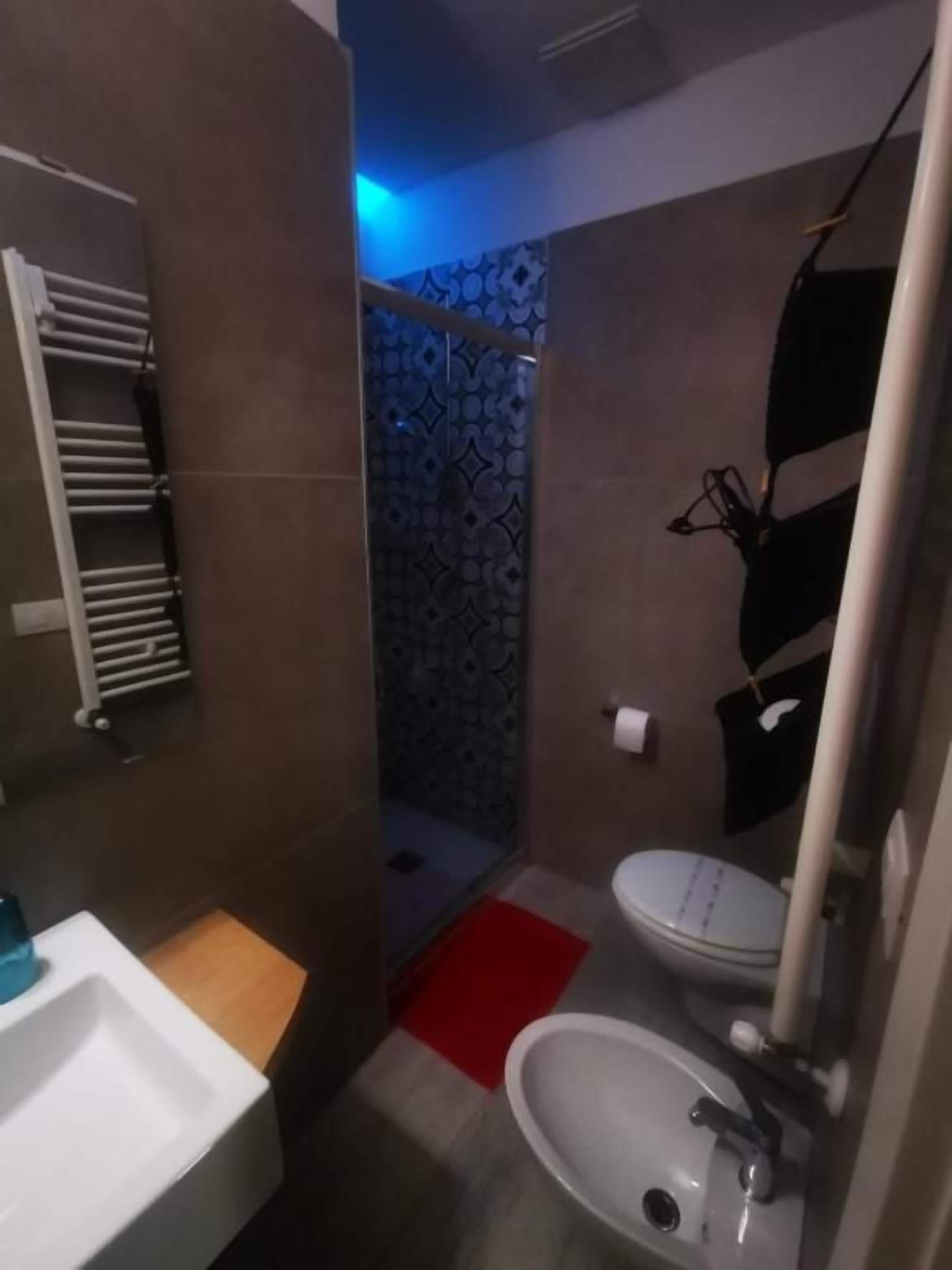 Casa de banho com lavatório branco, sanita e zona de duche.