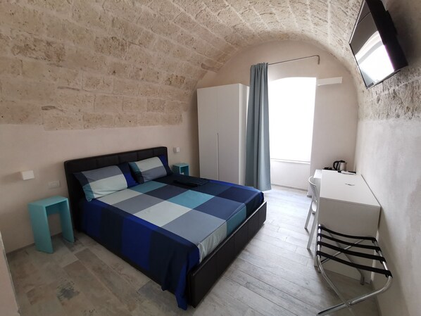 A bedroom with a bed, a desk, a chair, a wardrobe, and a TV mounted on the wall. - San Pietro al Borgo (Molfetta)