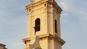 Un campanario de piedra histórico con elaboradas esculturas y una cruz en la parte superior.