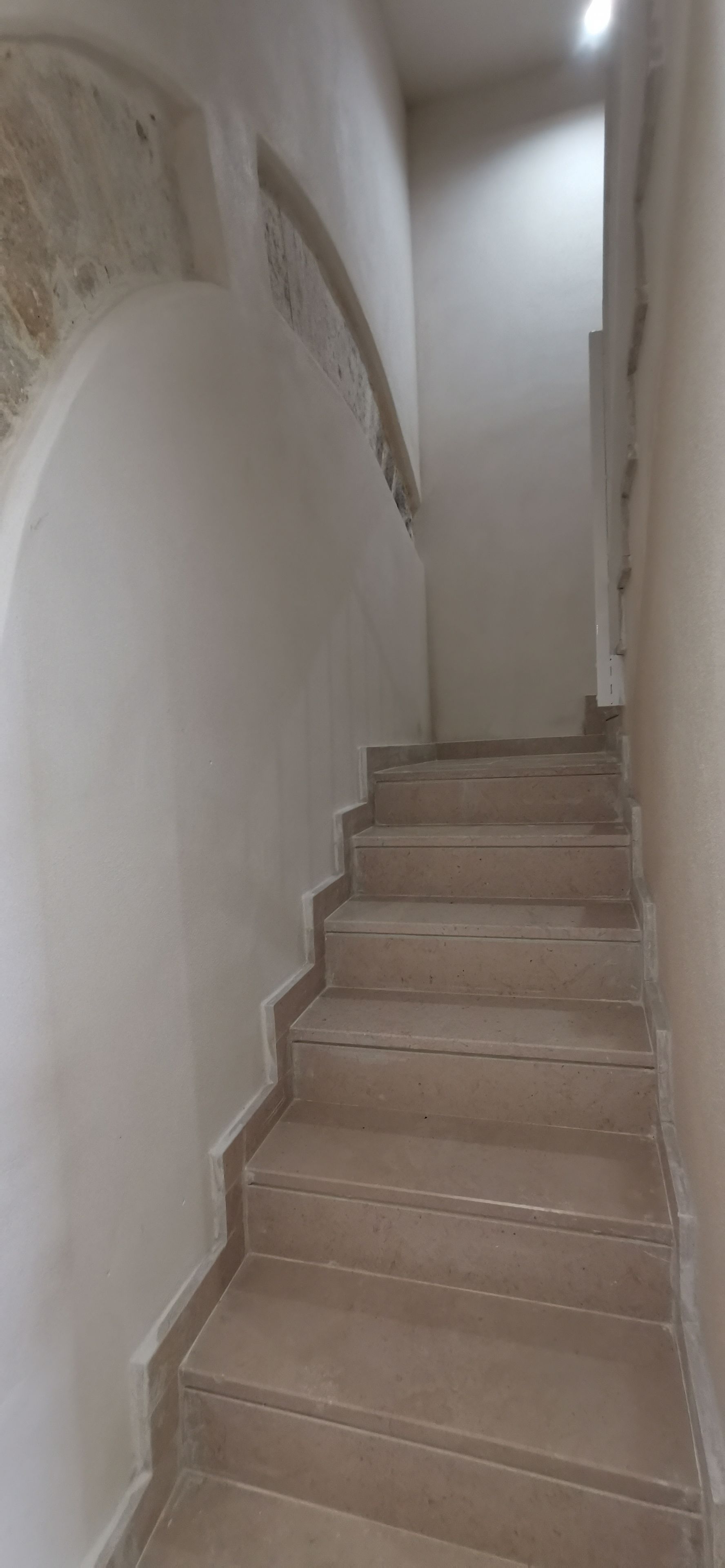 A staircase with a plain white wall on one side and a plain beige wall on the other.