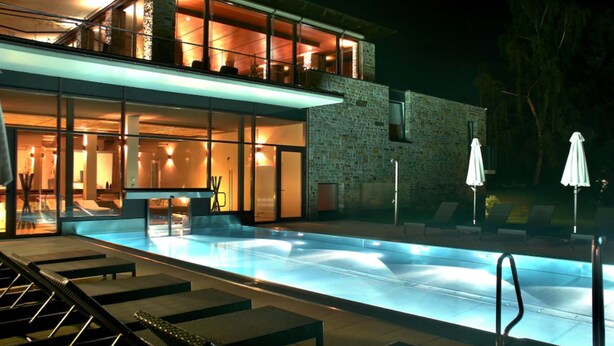 A modern hotel with a swimming pool, outdoor seating, and a stone facade. - Hotel Lauterbad (Freudenstadt)