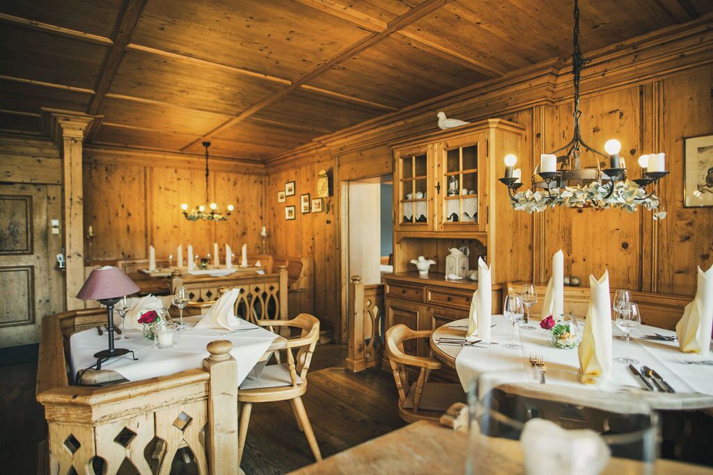 Ein Esszimmer mit Holztischen, gedeckten Plätzen, einer Kronleuchter und Holzschränken.