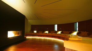 A modern room with a curved seating area, a fireplace, and a bed with a wooden headboard. - Hotel Lauterbad (Freudenstadt)