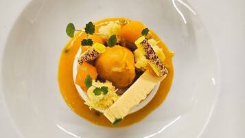 Un plato blanco con un postre que incluye una bola de helado, un trozo de pastel y salsa de caramelo.