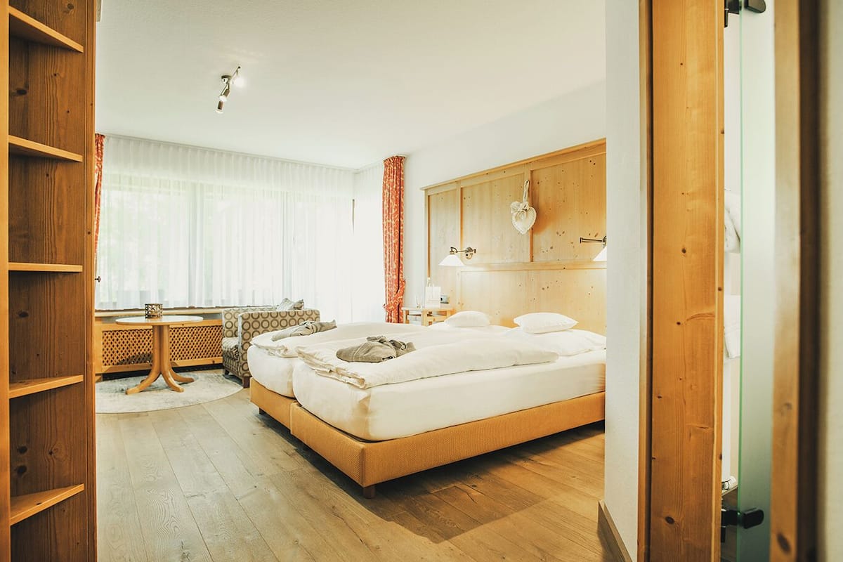A hotel room with a large bed, a desk, and a window with curtains.