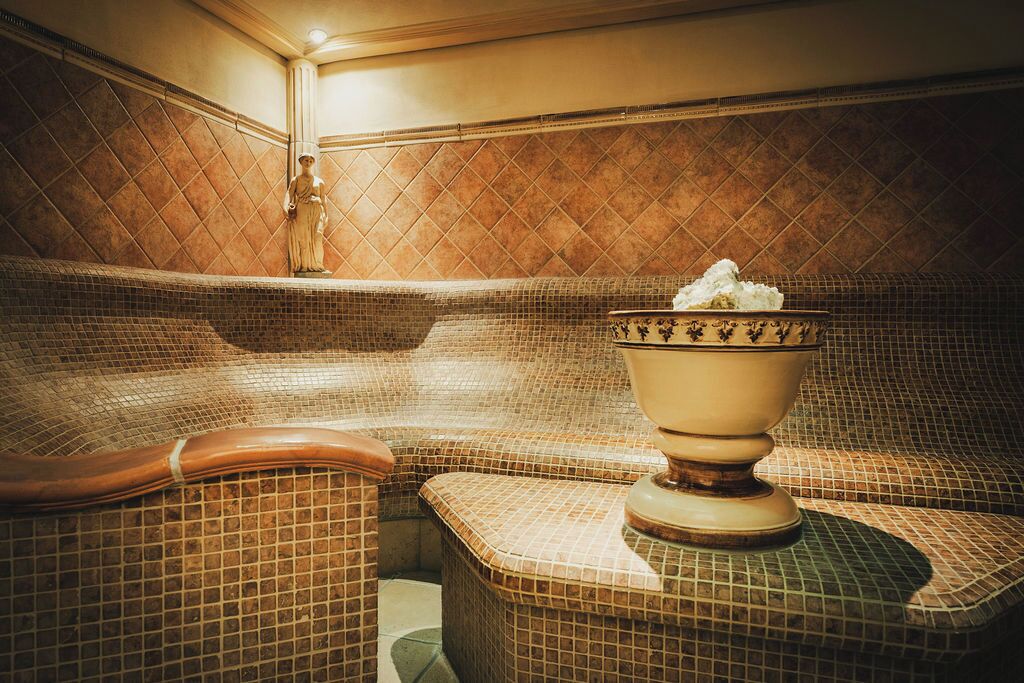 A spa area with a mosaic-tiled bench and a large ceramic basin.