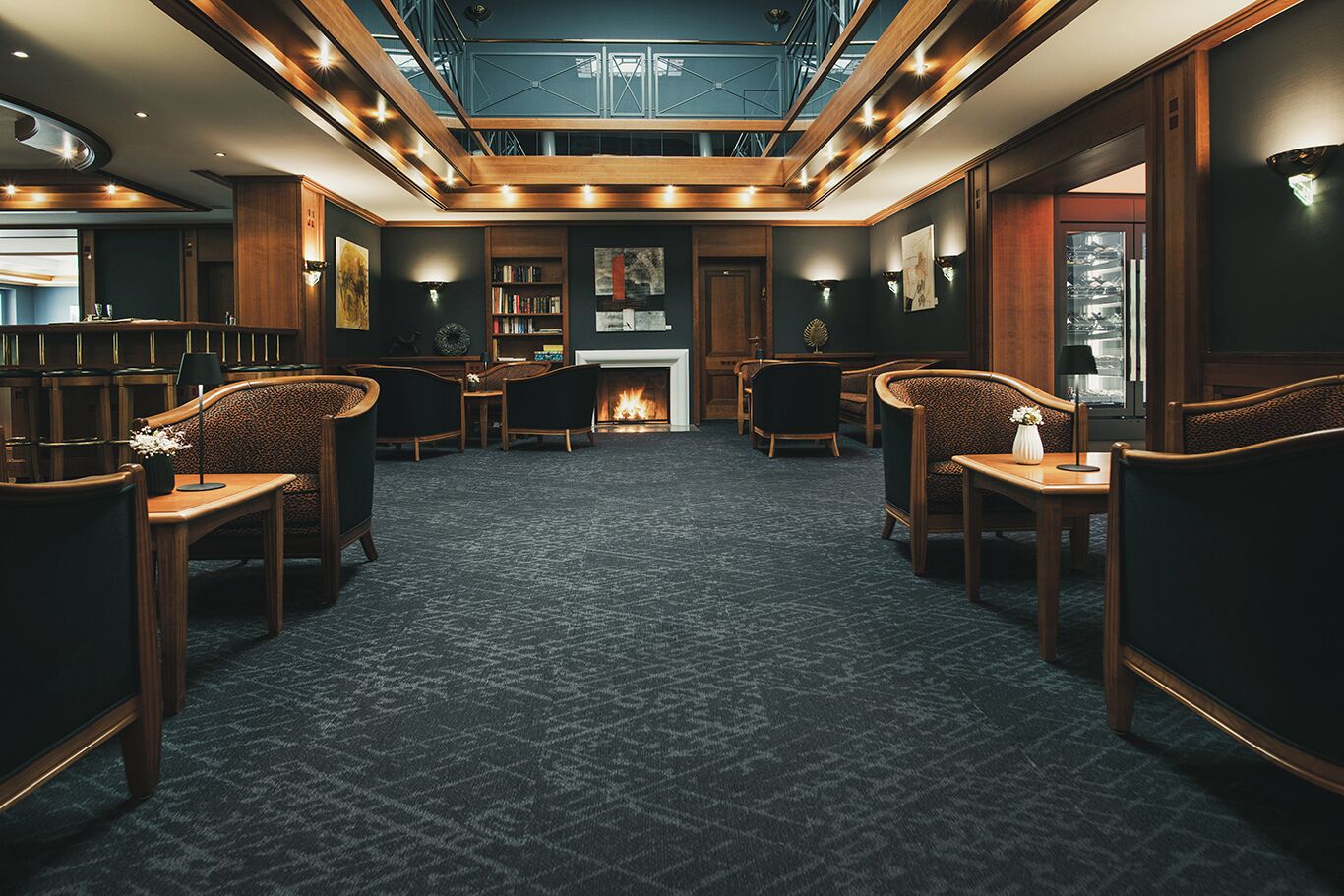 Una moderna area lounge con camino, posti a sedere confortevoli e un soffitto alto con lucernari.