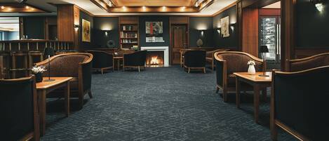 Una moderna area lounge con camino, posti a sedere confortevoli e un soffitto alto con lucernari.
