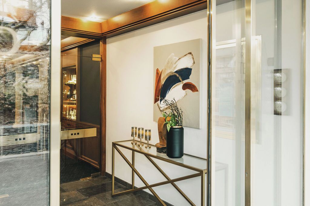 Un vestíbulo moderno de hotel con un separador de vidrio, un mostrador de recepción y un cuadro abstracto de gran tamaño.
