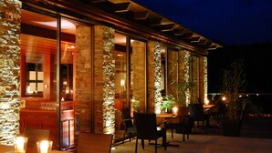 An outdoor patio area with stone columns, tables, chairs, and potted plants. - Hotel Lauterbad (Freudenstadt)