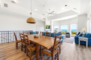 A spacious living area with a wooden dining table, blue sofa, and a balcony with a view.