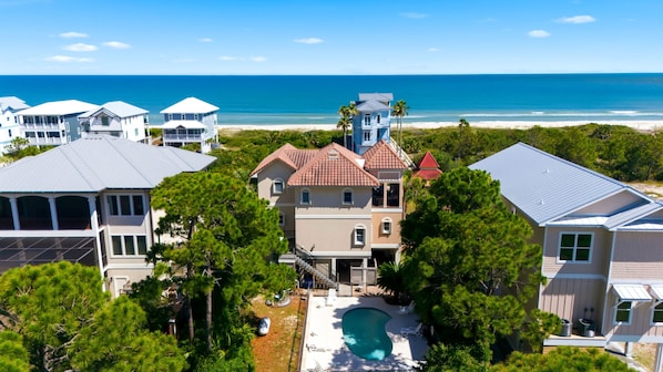 A residential area with multiple houses, a swimming pool, and a beach view.