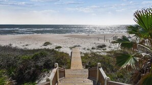 Un escalier en bois mène à une plage d’où l’on a une vue dégagée sur l’océan.