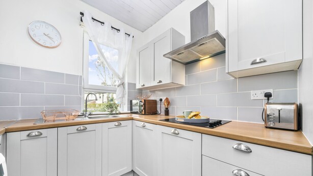 A modern kitchen with white cabinets, a wooden countertop, a stainless steel toaster, and a window with a view of greenery. - Two Bedroom Apartment by Klass Living Serviced Accommodation Motherwell - Anderson Apartment With WiFi &Parking (Motherwell)