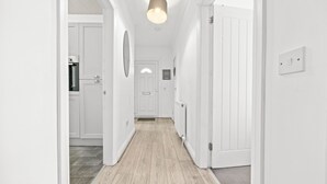 A hallway with white walls and wooden flooring, leading to a kitchen area with white cabinets and a refrigerator. - Two Bedroom Apartment by Klass Living Serviced Accommodation Motherwell - Anderson Apartment With WiFi &Parking (Motherwell)