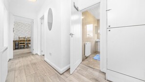 A hallway with a wooden floor, white walls, and a door leading to a bathroom with a toilet and sink. - Two Bedroom Apartment by Klass Living Serviced Accommodation Motherwell - Anderson Apartment With WiFi &Parking (Motherwell)