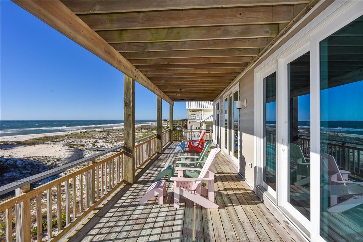 A wooden deck with a glass balustrade overlooking a beach.
