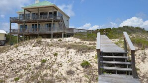 A multi-story beachfront house with a wooden deck leading to the entrance. - TRADEWINDS HAS LONG BEEN praised as a uniquely appointed home where treasured memories are made. (St. George Island)