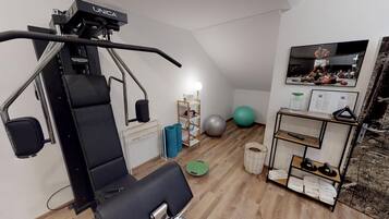 A compact gym with a pull-up bar, exercise balls, and a small shelf with towels.