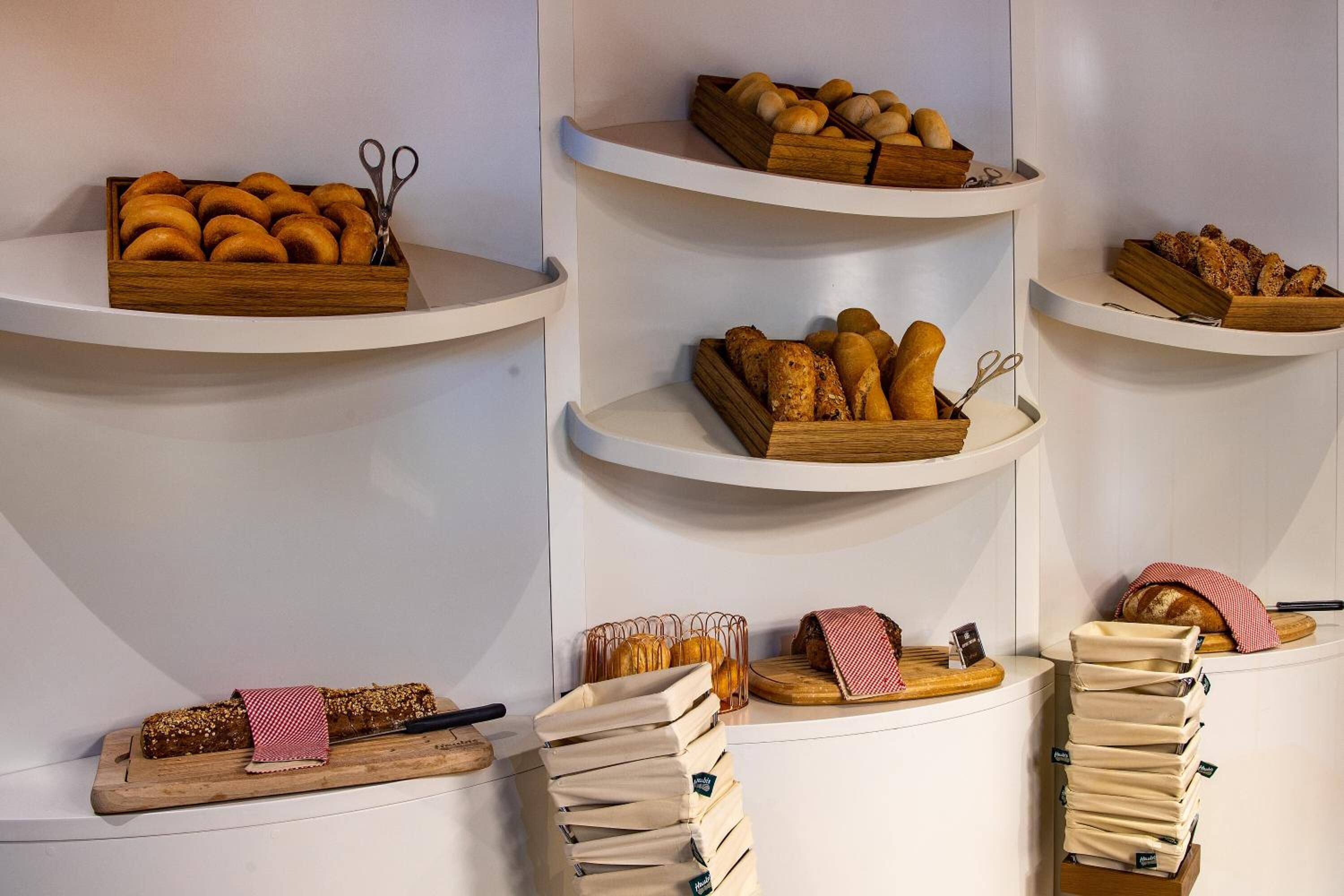 A bakery display with various breads and pastries on shelves.
