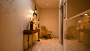 A modern hallway with a wooden console table, a chair, and a glass partition. - Hotel Seven (Villach)