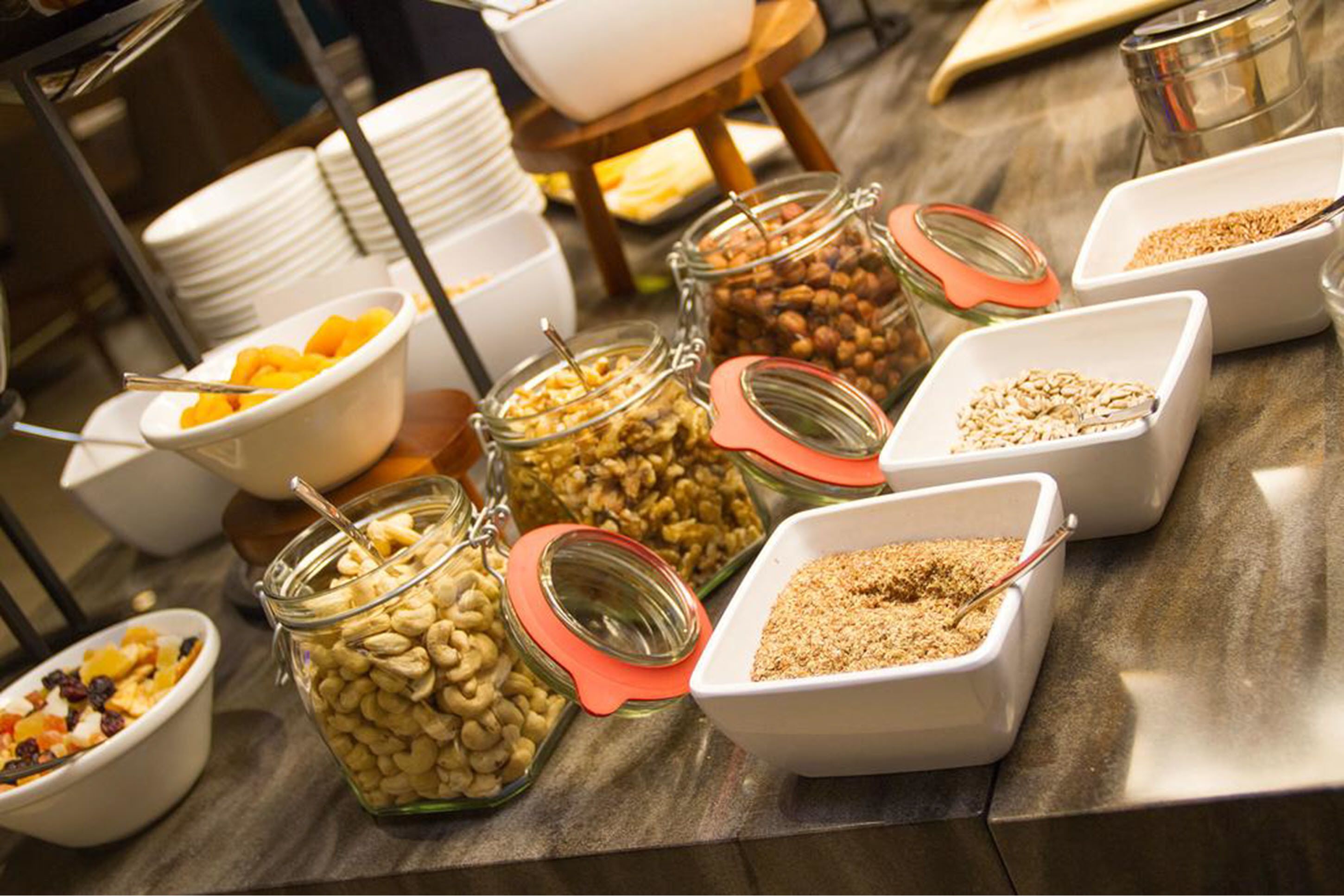 Una mesa de buffet con diversos alimentos, como nueces, frutas secas y granola.