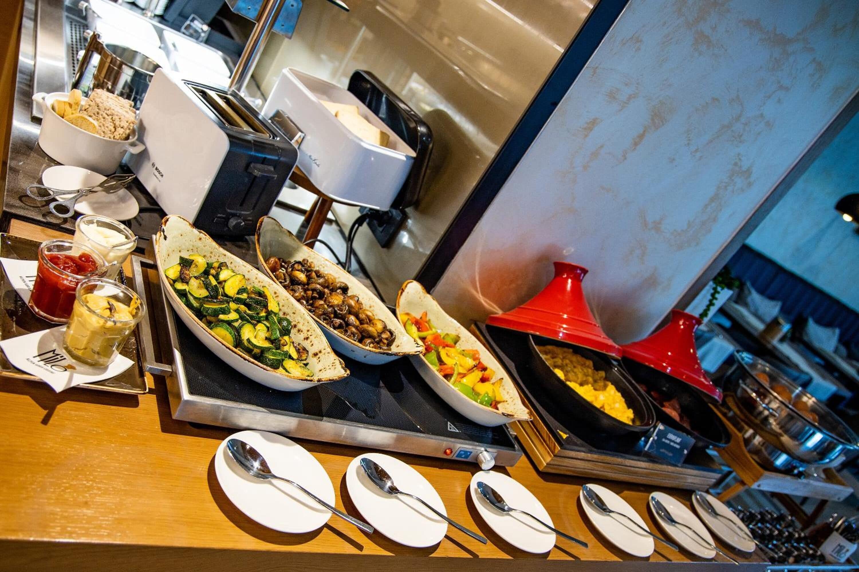 Un buffet proposant divers plats, notamment des salades, des légumes et un récipient contenant une sauce rouge.