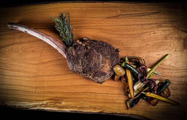 Un plato de carne con verduras sobre una tabla de madera.