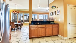 A kitchen with wooden cabinets, a black countertop, and a dining area with a table and chairs.