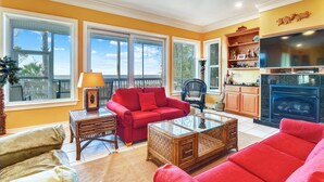 A living room with a red sofa, glass coffee table, and a fireplace.