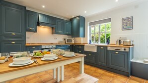 A modern kitchen with dark blue cabinets, a wooden countertop, and a window providing natural light.