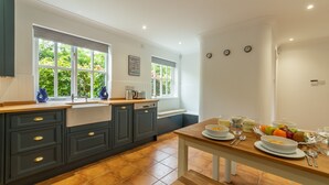 A modern kitchen with dark cabinets, a wooden countertop, and a dining table set with plates, bowls, and fruits.