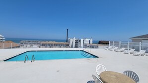A rooftop pool with a clear view of the ocean, white lounge chairs, and a sign for 'Ocean Break Condos'. - 🏖️Ocean Views, Newly Renovated🏖️ (Ocean City)