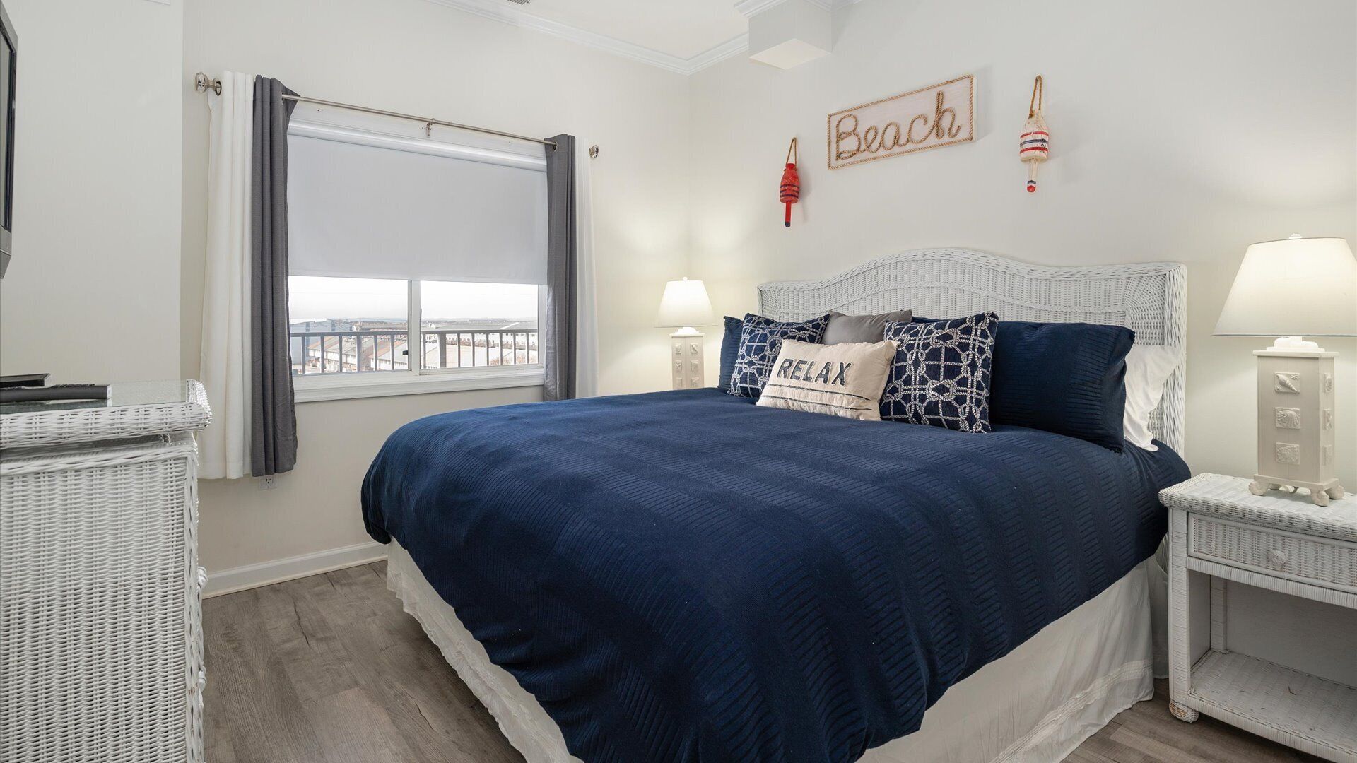 Une chambre avec un grand lit, deux tables de chevet, une fenêtre avec des rideaux et une vue sur la ville.
