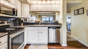 A modern kitchen with white cabinets, stainless steel appliances, and a central island. - Located right on the beachfront, this beautiful well-appointed Villa offers you fabulous views. (St. George Island)