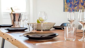Una mesa de comedor dispuesta con platos, vasos y un cuenco de fruta.