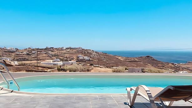 Un área de piscina con vista despejada al océano y un paisaje rocoso al fondo.