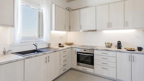 Una cocina moderna con armarios blancos, un lavamanos de acero inoxidable y un horno empotrado.