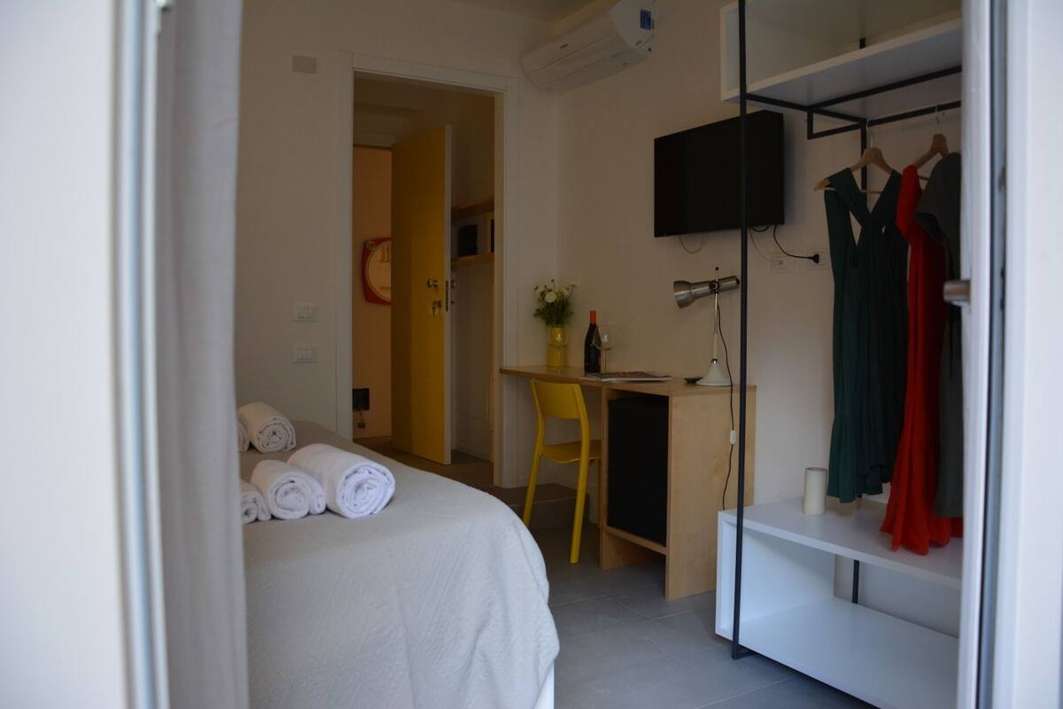 Une chambre d’hôtel équipée d’un lit, d’un bureau, d’une télévision et d’une armoire.