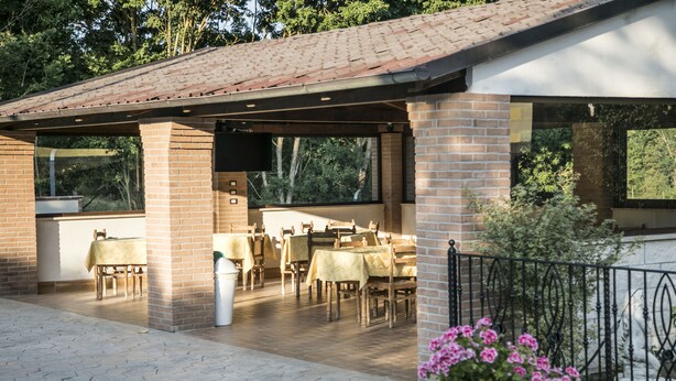 An outdoor patio with brick walls, tables, and chairs. - Hotel Ristorante Il Giardino (Cagnano Amiterno)
