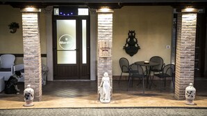 A restaurant entrance with a tiled roof, a glass door with 'Il Giardino' signage, outdoor seating, and decorative urns. - Hotel Ristorante Il Giardino (Cagnano Amiterno)