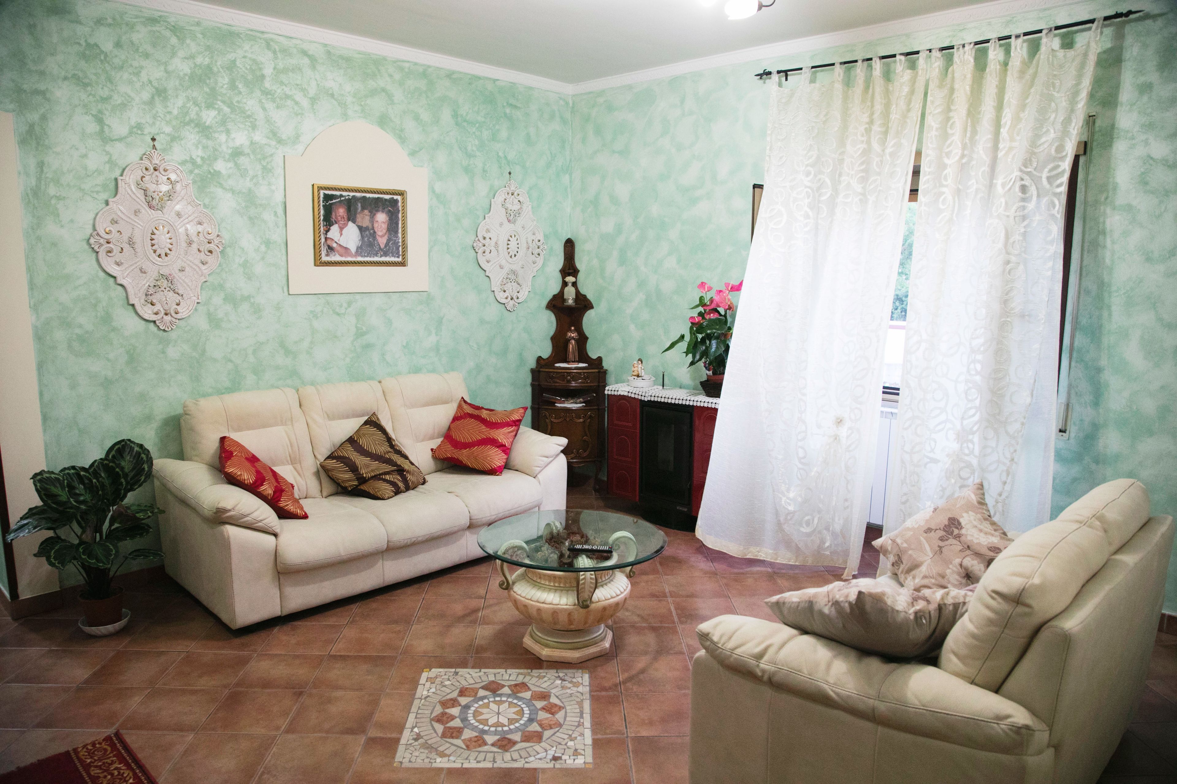 A living room with a sofa, armchair, glass coffee table, and decorative items.