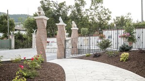 A landscaped entrance with a brick pathway, metal fence, and decorative lion statues. - Hotel Ristorante Il Giardino (Cagnano Amiterno)