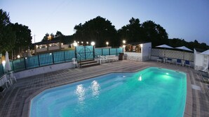 A rectangular swimming pool with a tiled deck, surrounded by a low fence and a few lounge chairs. - Hotel Ristorante Il Giardino (Cagnano Amiterno)
