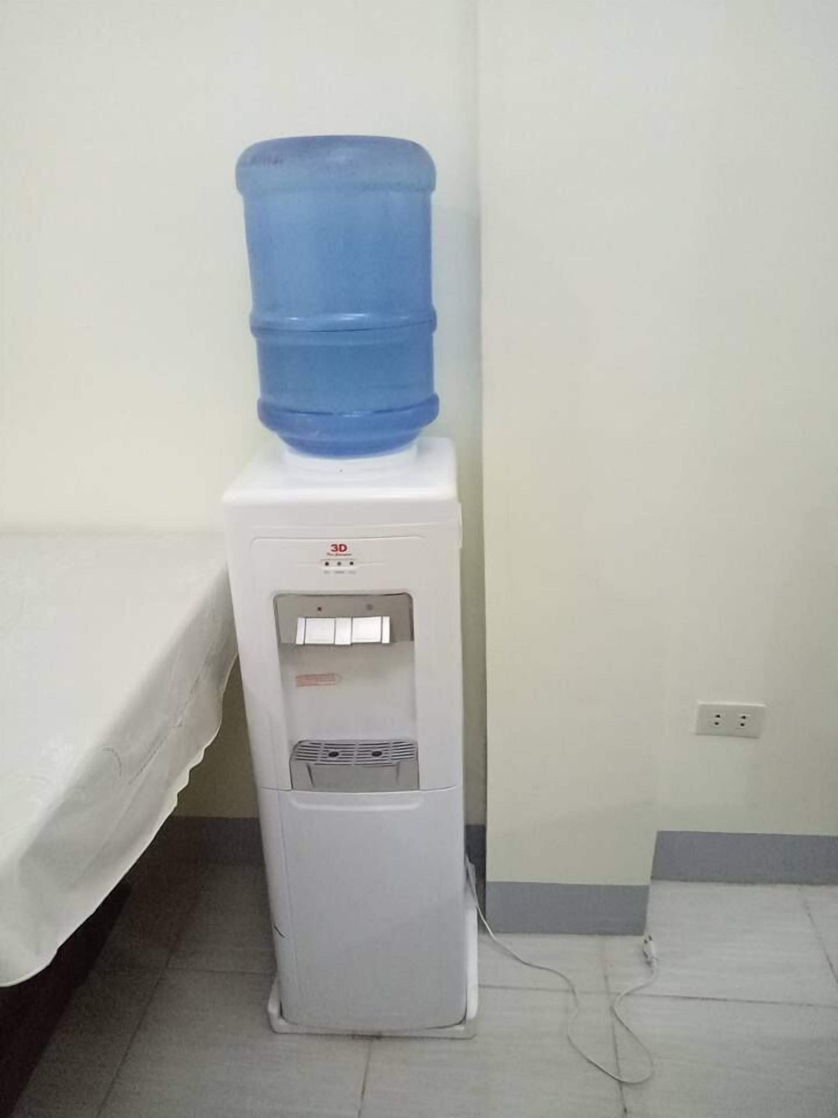 A water dispenser with a large blue water jug on top, a control panel, and a water filter compartment.