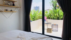 A bedroom with a large window, a bed, a small table, and a chair. - Green Peace Da Nang (Da Nang)
