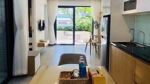 A modern kitchen with a dining area, a large window, and a view of greenery outside. - Green Peace Da Nang (Da Nang)